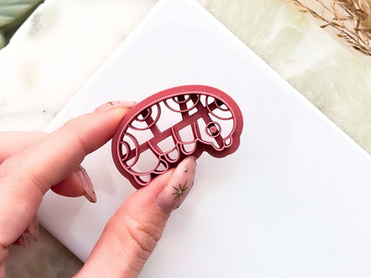 Close up of grub insect polymer clay shape cutter showing leg, eye and pattern details.
