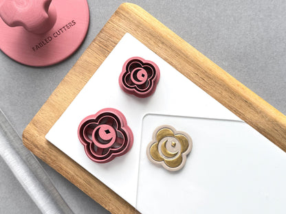 Crescent moon and star polymer clay cutters in two sizes, featuring a crescent moon centred within a decorative flower-shaped frame, displayed beside a matching finished clay embellishment in gold.