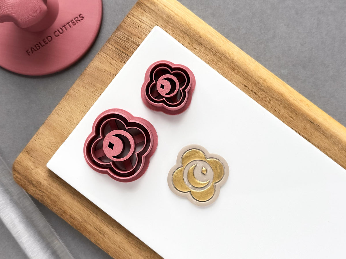 Crescent moon and star medallion polymer clay cutters in two sizes, featuring a decorative scalloped outline and a central crescent moon design, displayed beside a matching gold-coloured clay embellishment.