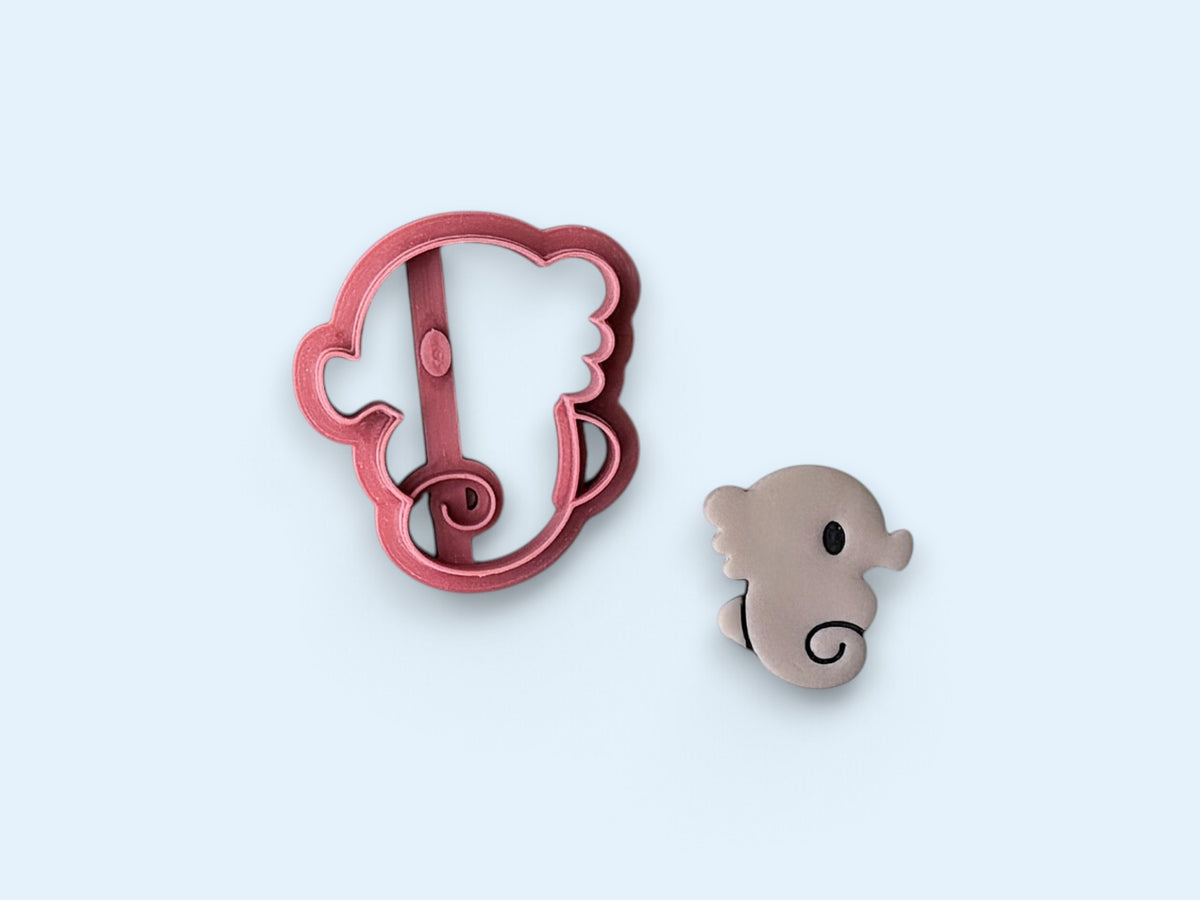 cute seahorse shaled clay cutter in pink with a polymer clay cut out sample beside it on a blue background