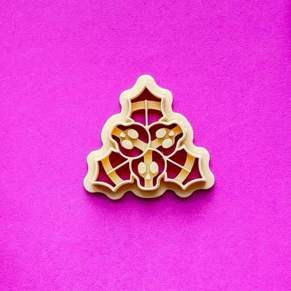 single beige holly clay cutter on purple contrasting background.