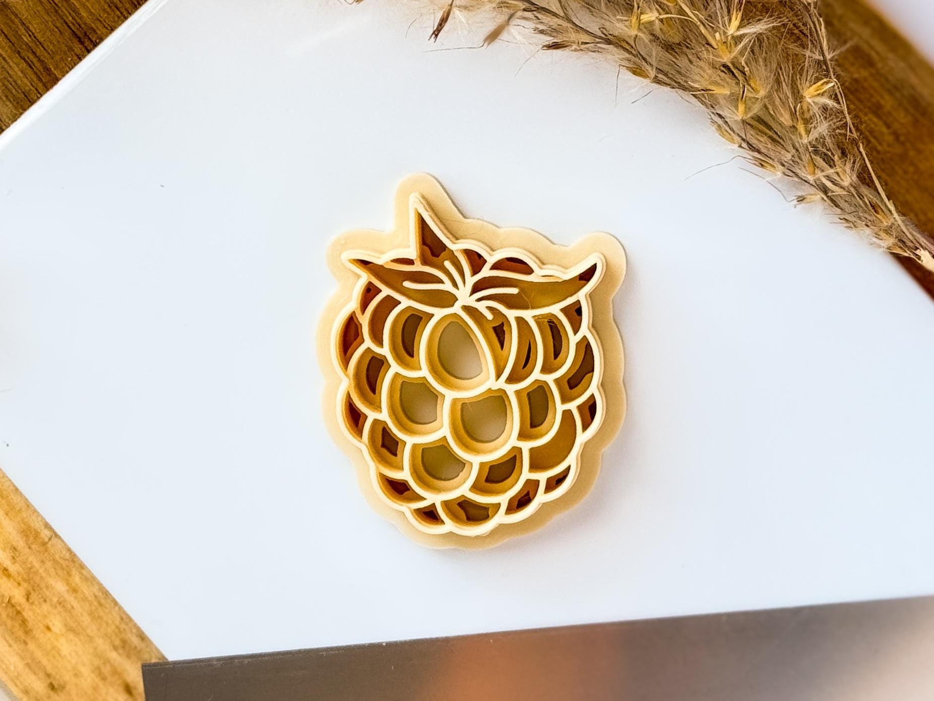 Beige raspberry clay cutter stamp on white tile