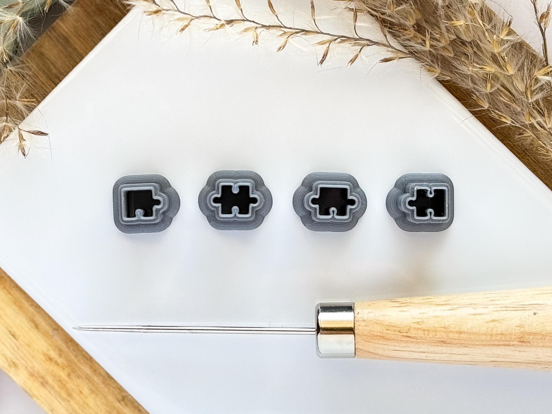 Micro clay cutter set of 4 puzzle pieces in silver on a white tile