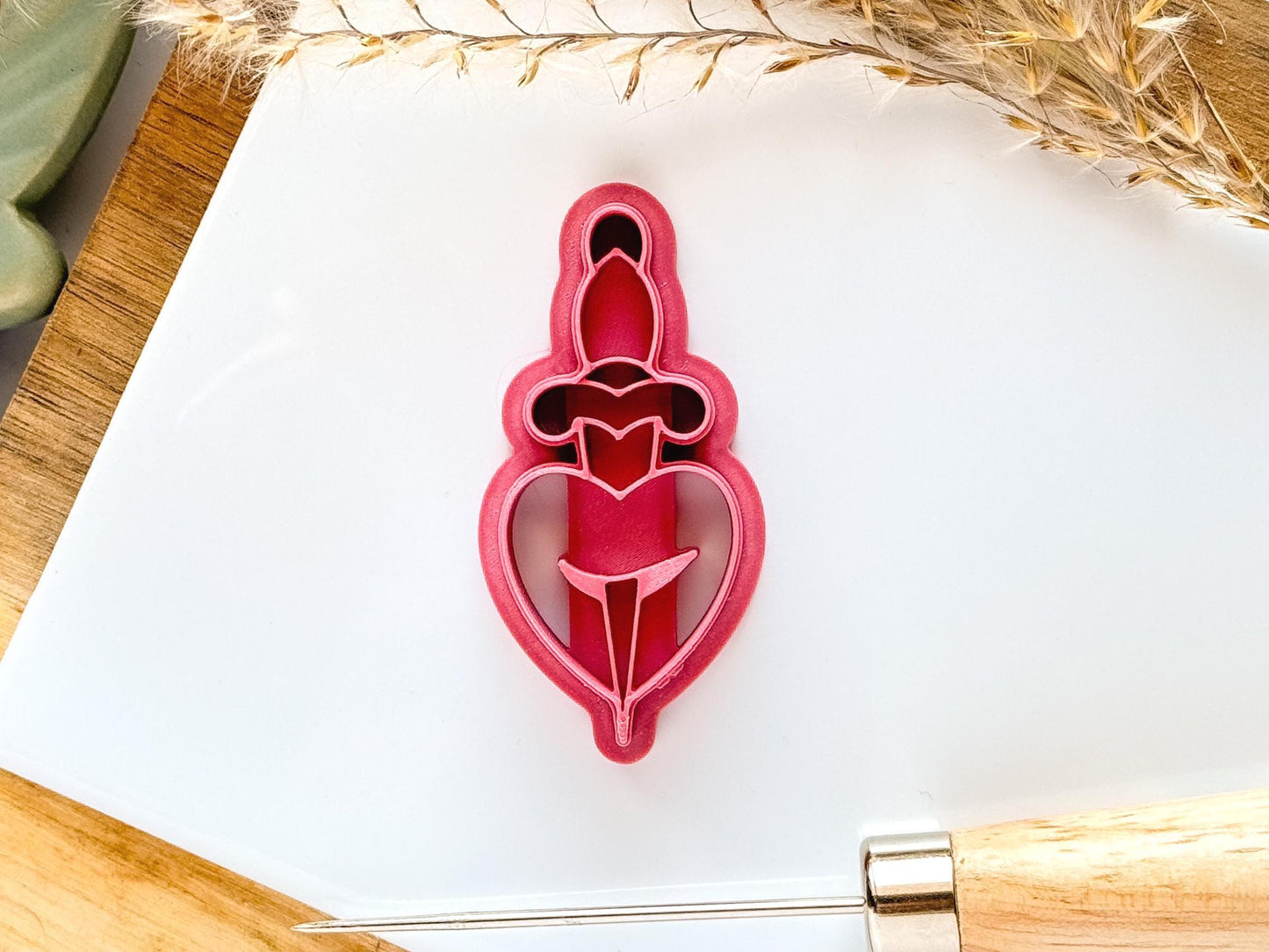 Dark pink clay cutter in shape of heart with dagger