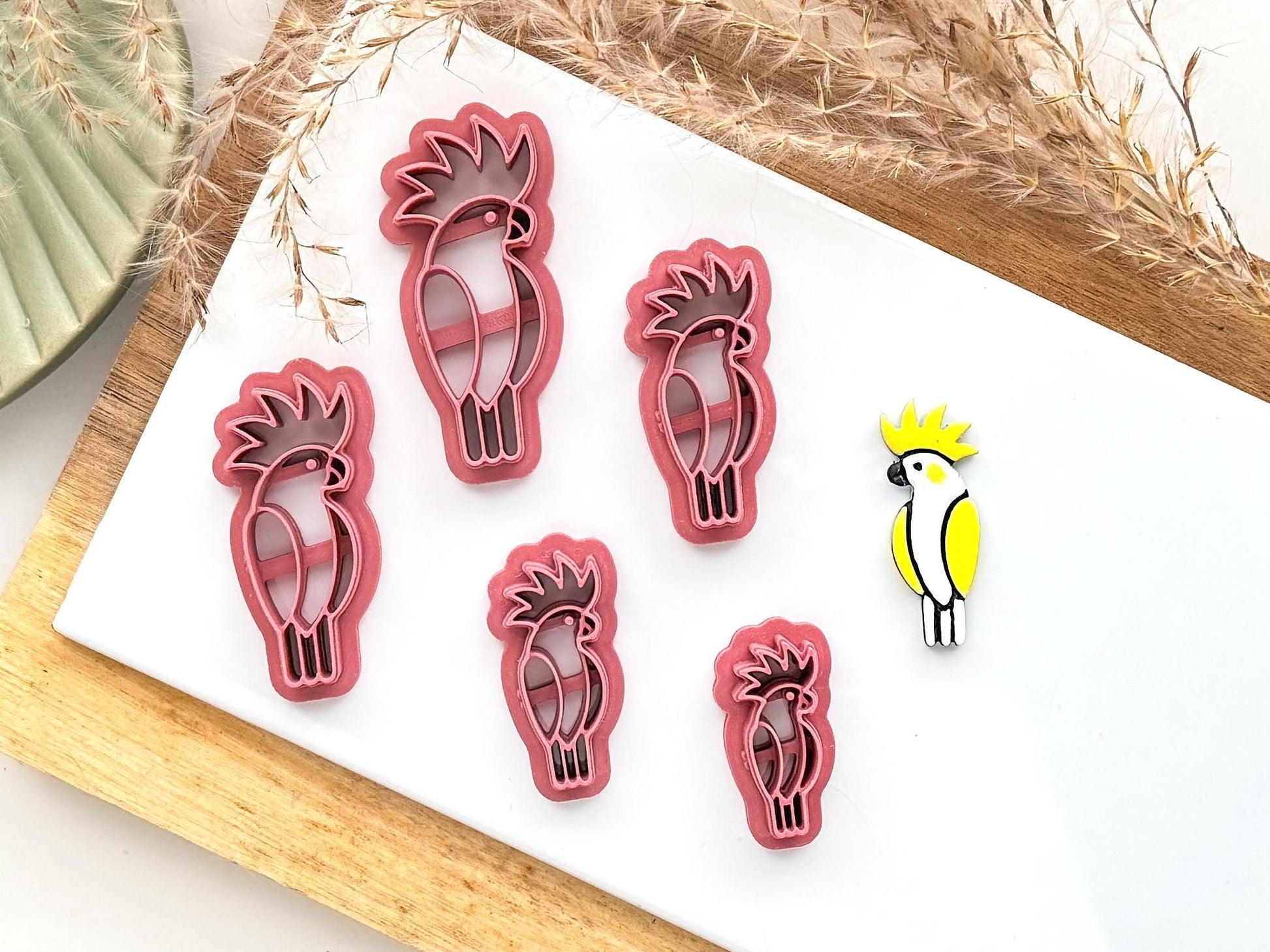 Various sizes of cockatoo or cockatiel polymer and silver clay cutter with a sample cut out on a white tile