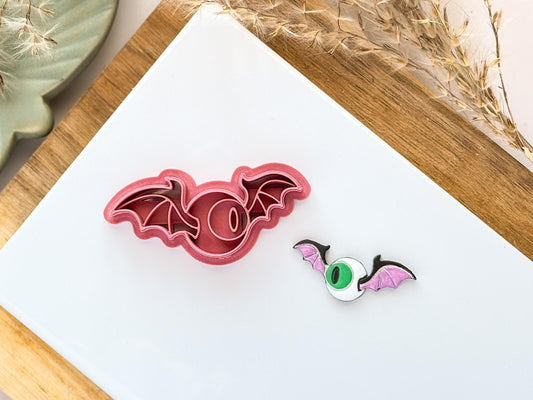 Flying eye ball polymer clay cutter in pinkon a white tile background with finish clay sample