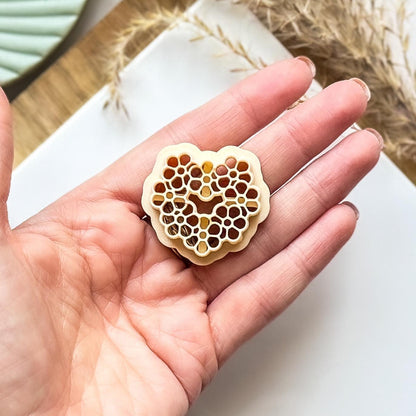 Beige floral clay cutter with flower stamps being held in a hand