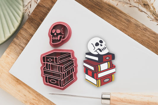polymer clay cutter in the shape of a stack of books with labels and cover details with a separate side facing skull cutter.