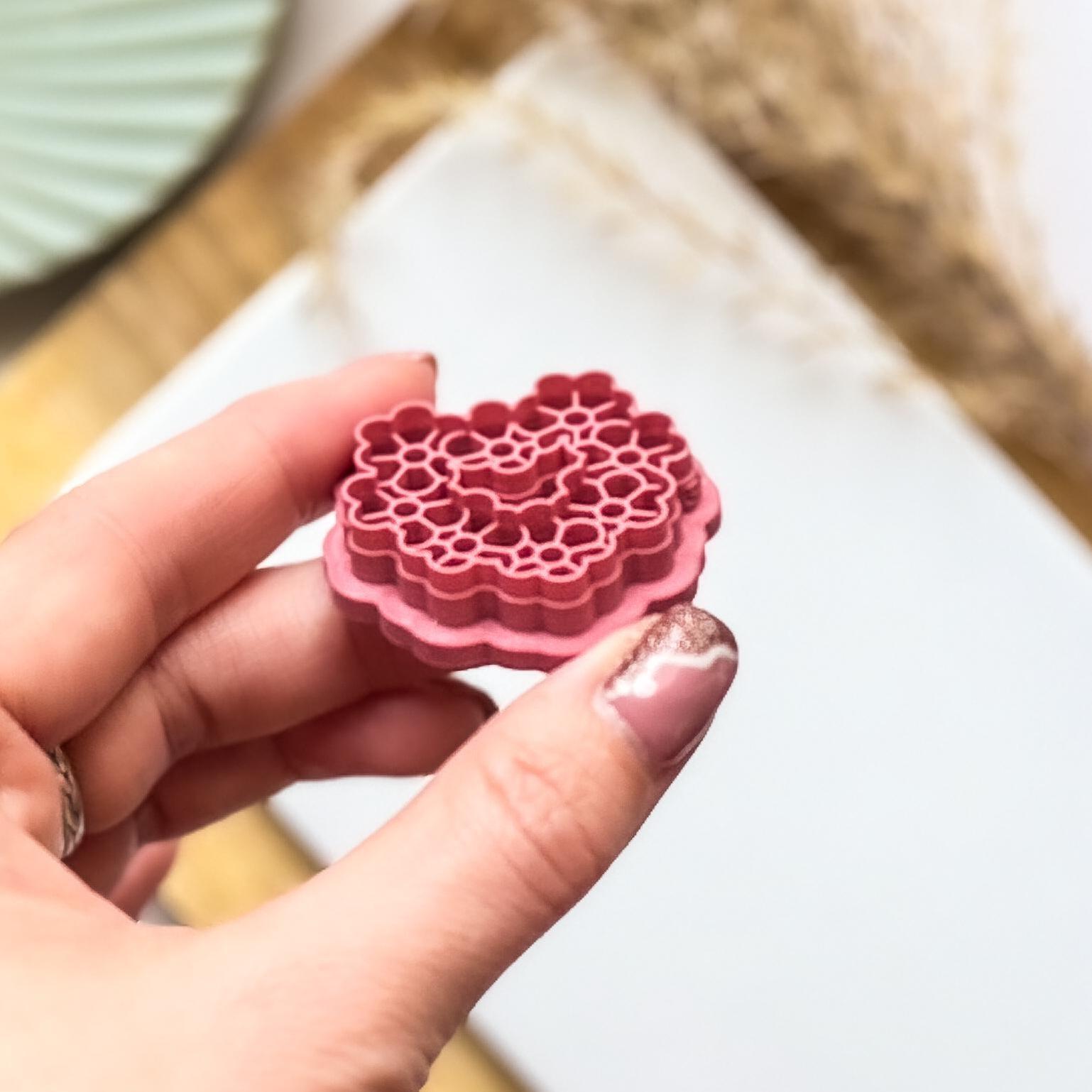 Tilted view of a daisy heart polymer clay cutter to show the depth of the flower imprint lines and sharp cutting edge