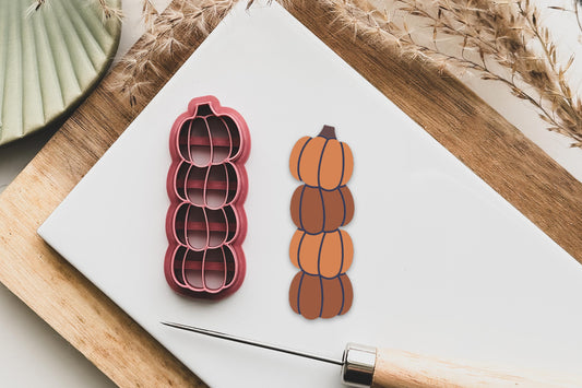 Polymer clay cutter in the shape of 4 stacked pumpkins. Long, thin shape with imprint lines to highlight the pumpkin&#39;s sections and stalk at the top of the cutter.