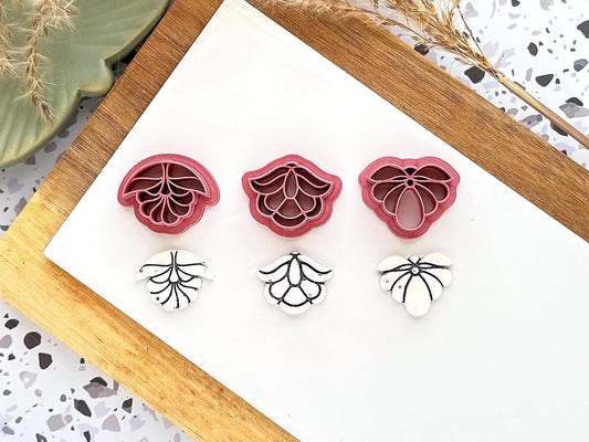 image of 3 art deco style flower clay cutters with glitter white polymer clay samples underneath.