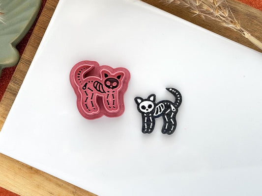 pink clay cutter in the shape of a cat with skeleton embossed details for Halloween