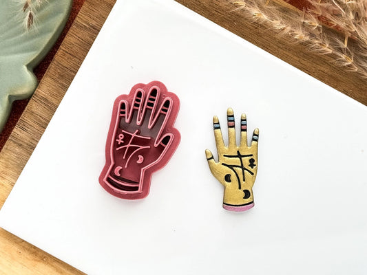 Witch hand clay cutter with witch mark stamp details. Part of the Fabled Cutters Halloween collection. Gold painted polymer clay hand to the right,