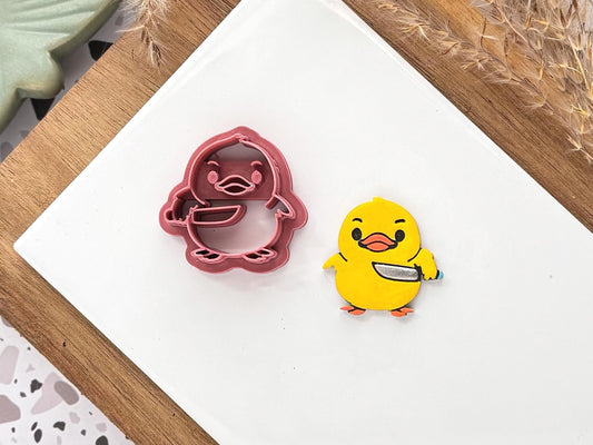 Clay cutter in the shape of a chick holding a knife