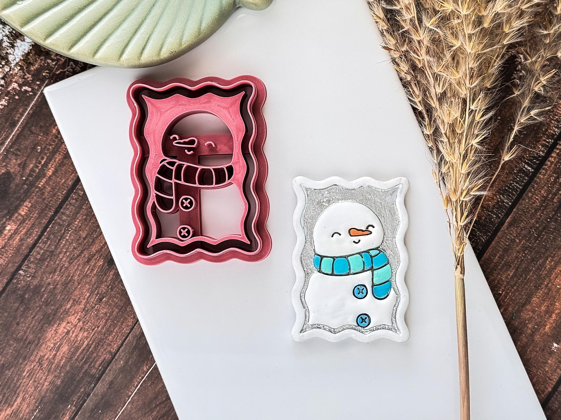 Pink smiling snowman clay cutter with scarf and carrrot nose details.