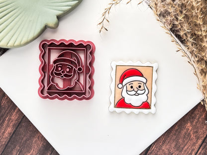Pink Christmas santa stamp clay cutter with face details and wavy edges, next to the cutter is a polymer clay sample painted in red and white.