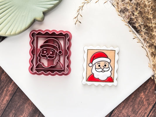 Pink Christmas santa stamp clay cutter with face details and wavy edges, next to the cutter is a polymer clay sample painted in red and white.