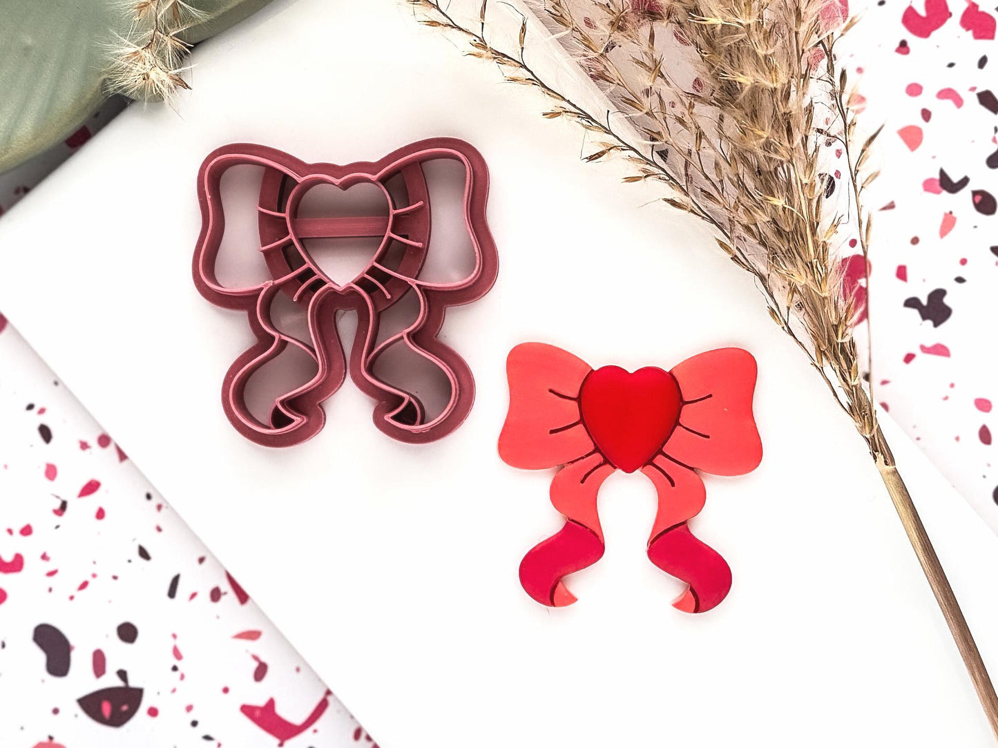 bow shaped polymer clay cutter with heart shaped center and trailing ribbon ends.