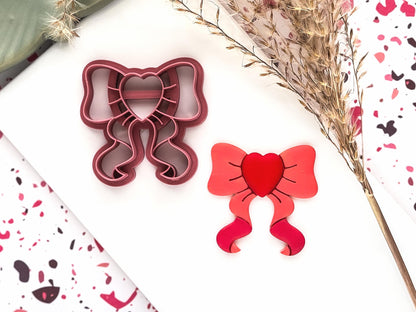 bow shaped polymer clay cutter with heart shaped center and trailing ribbon ends.