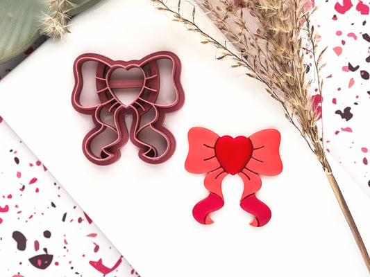 bow shaped polymer clay cutter with heart shaped center and trailing ribbon ends.