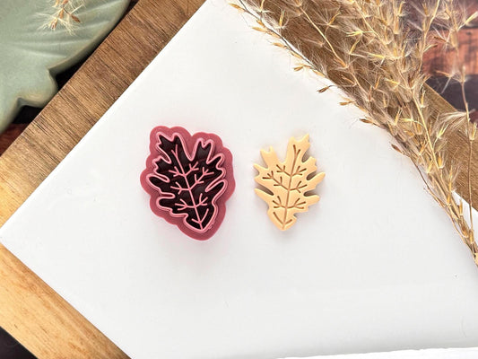 Asymmetric pointed leaf clay cutter. UK-made polymer clay tool botanical design with vein stamp details on a white baking tile. 