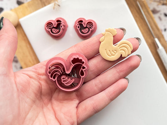 Rooster shaped polymer clay cutter in a hand with a beige clay cut out sample shape.