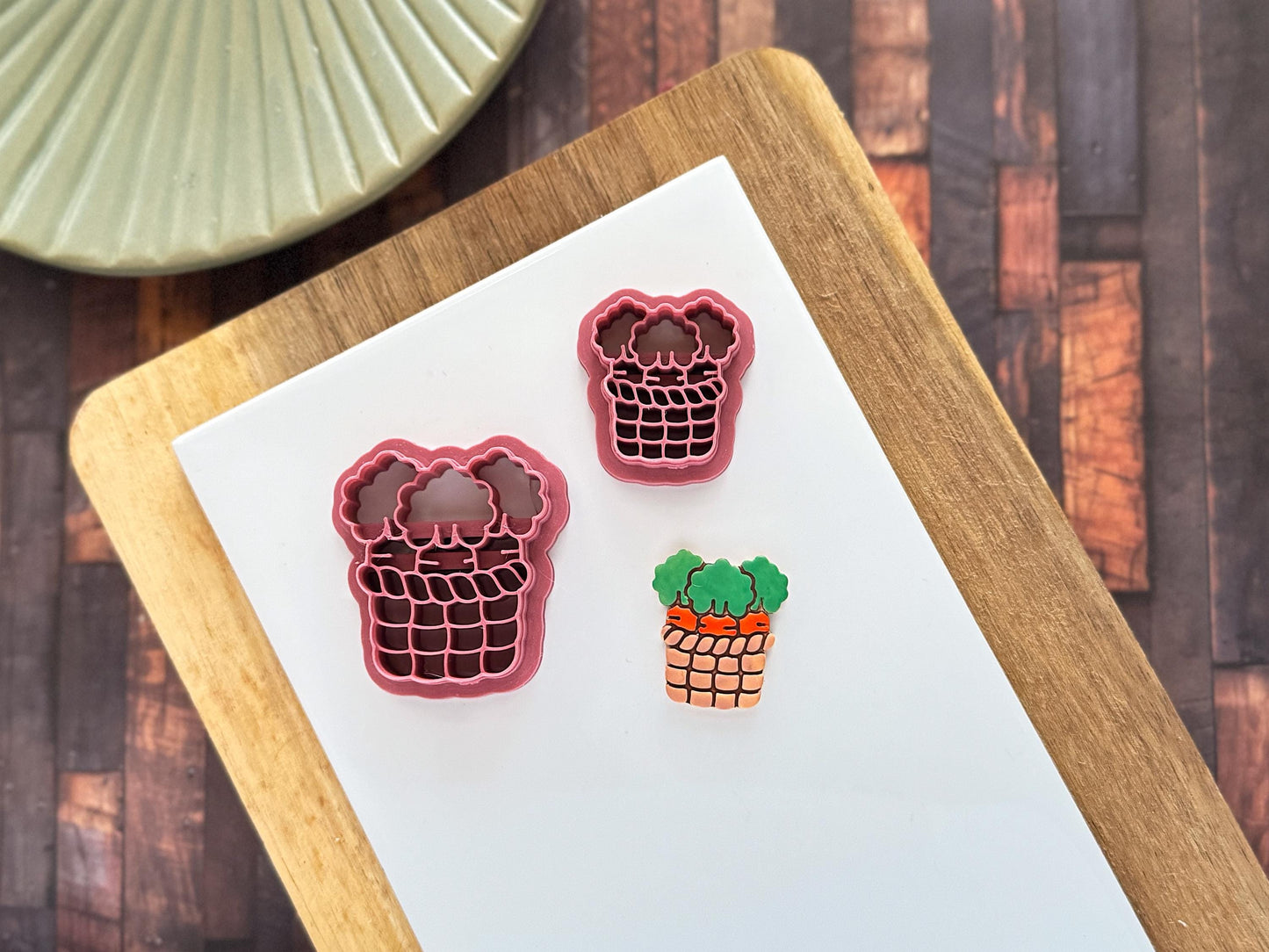 Clay cutter in the shape of a woven basket with 3 carrots inside alongside a polymer clay sample of the cut out and painted piece.
