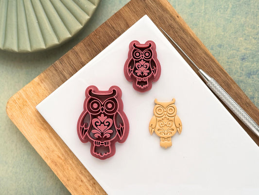 Pink decorative boho horned owl clay cutter in small and large sizes with floral style patterns. Next to the cutters is a beige polymer clay cut out sample