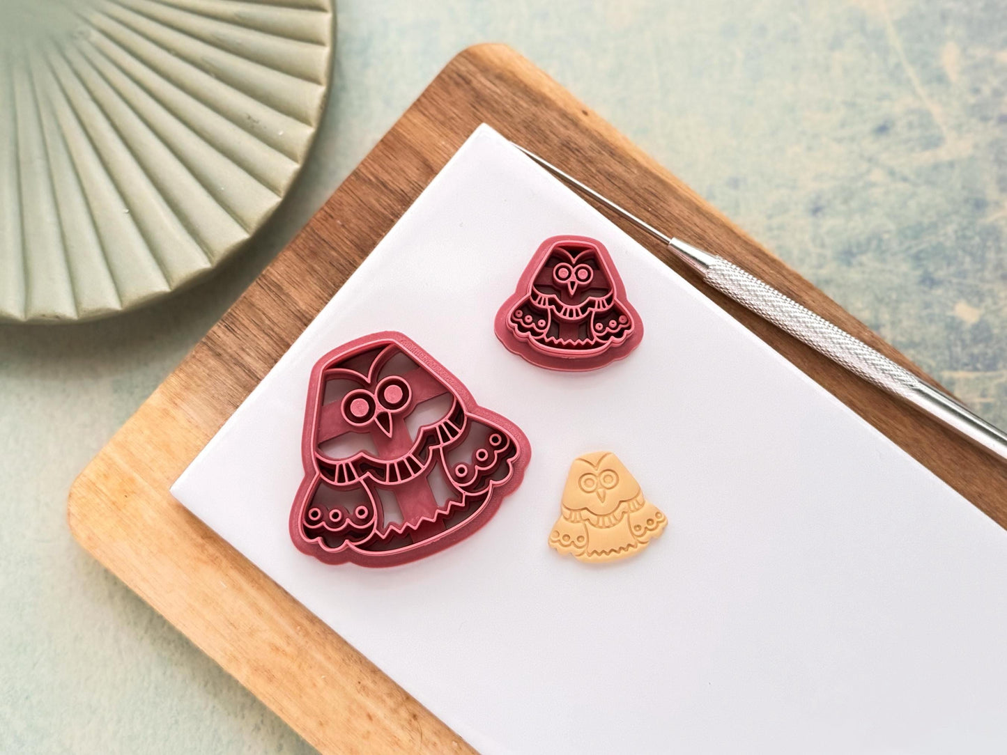 Cartoon owl clay cutter in small and large sizes with decorative imprint details. Next to the cutter is a beige polymer clay sample cut out showing the details and clean finish.