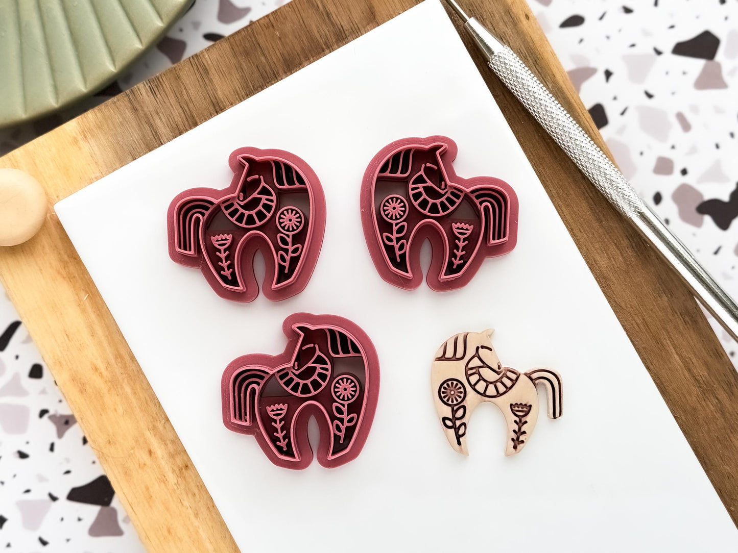 Scandi style horse shaped polymer clay cutter in a mirrored pair and single shape next to a beige clay cut out sample.