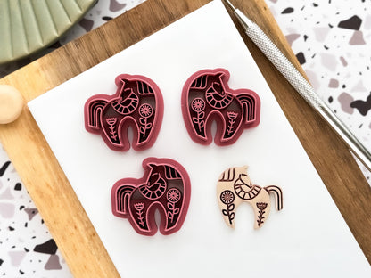 Scandi style horse shaped polymer clay cutter in a mirrored pair and single shape next to a beige clay cut out sample.