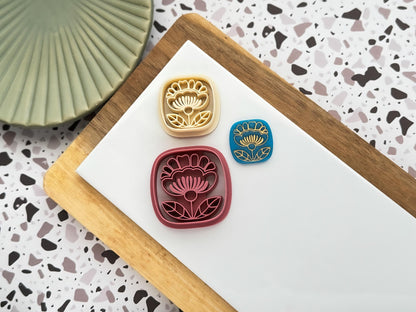 Boho Themed square polymer clay cutters with folk art style stamp details and blue polymer clay cut out sample with gold pattern on a white clay baking tile.