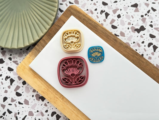 Boho Themed square polymer clay cutters with folk art style stamp details and blue polymer clay cut out sample with gold pattern on a white clay baking tile.