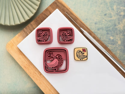 Large single and small mirrored pair of square clay cutters with a cute bird holding a flower stamp detail. Next to them is a beige polymer clay cut out of the smaller cutter.