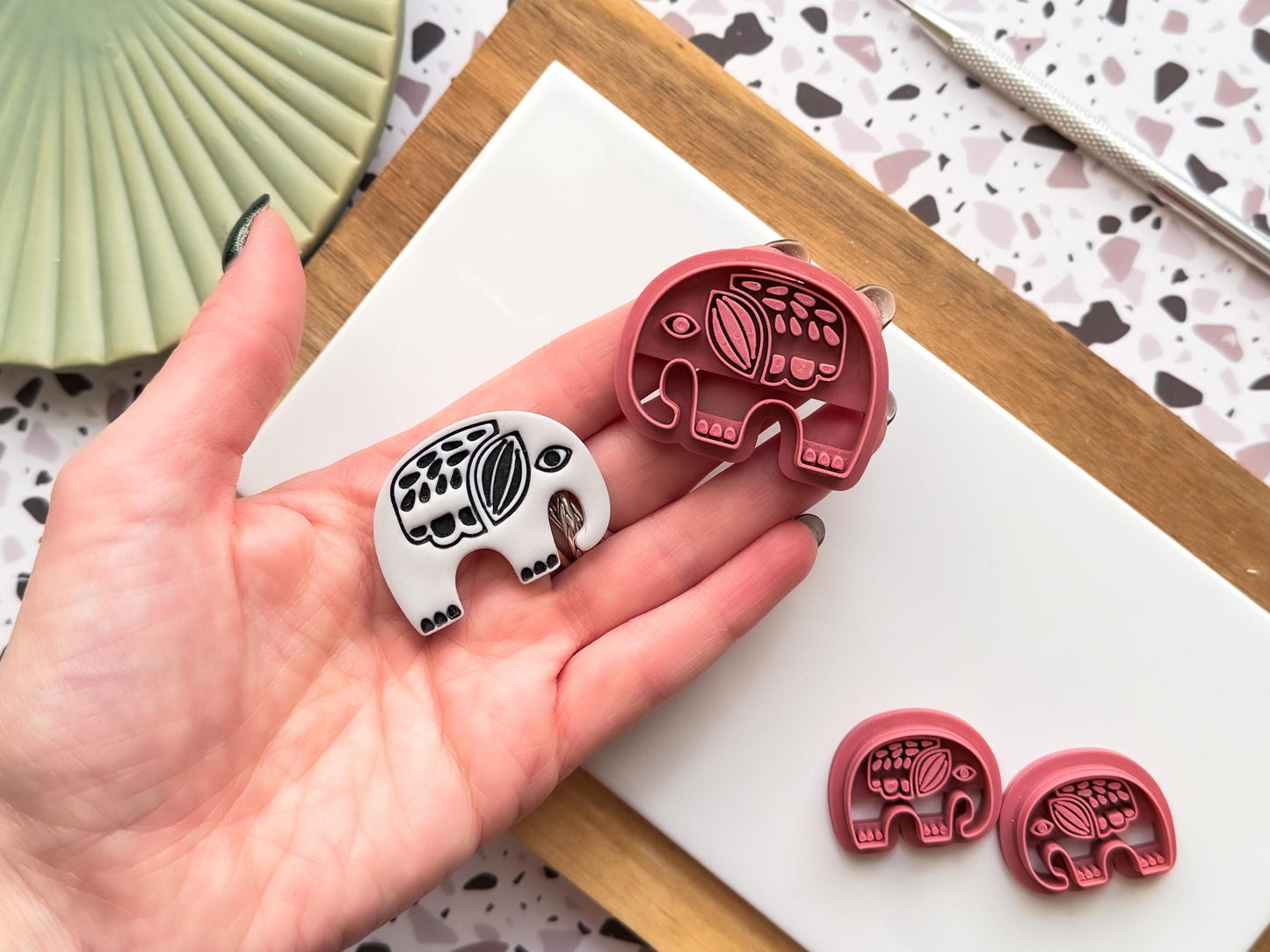 4cm Tribal elephant clay cutter being held in a hand with a sample polymer clay cut out for scale