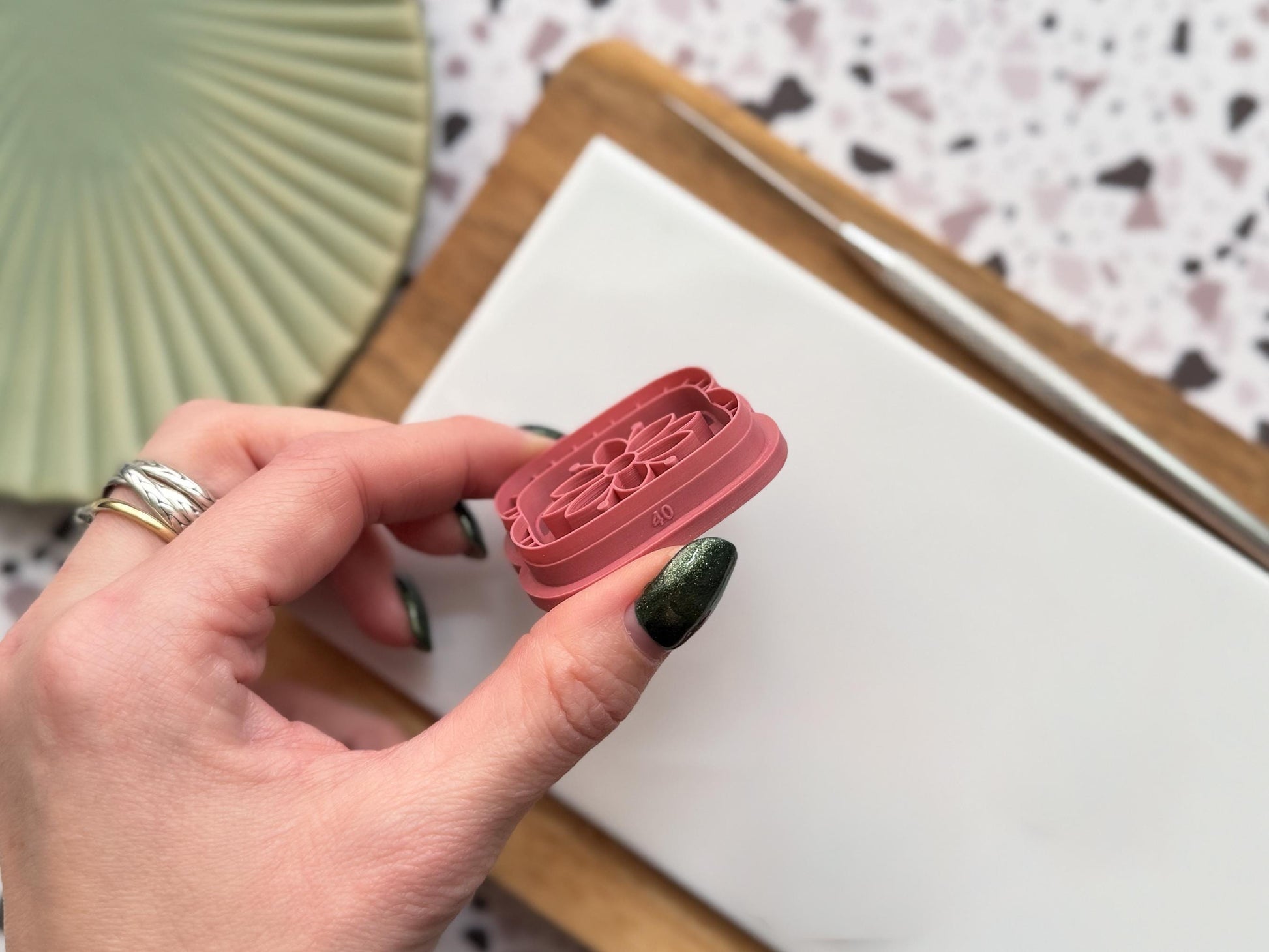 this image contains a polymer clay cutter being held and tilted to the side to show the sharp cutting edge and the measurement.