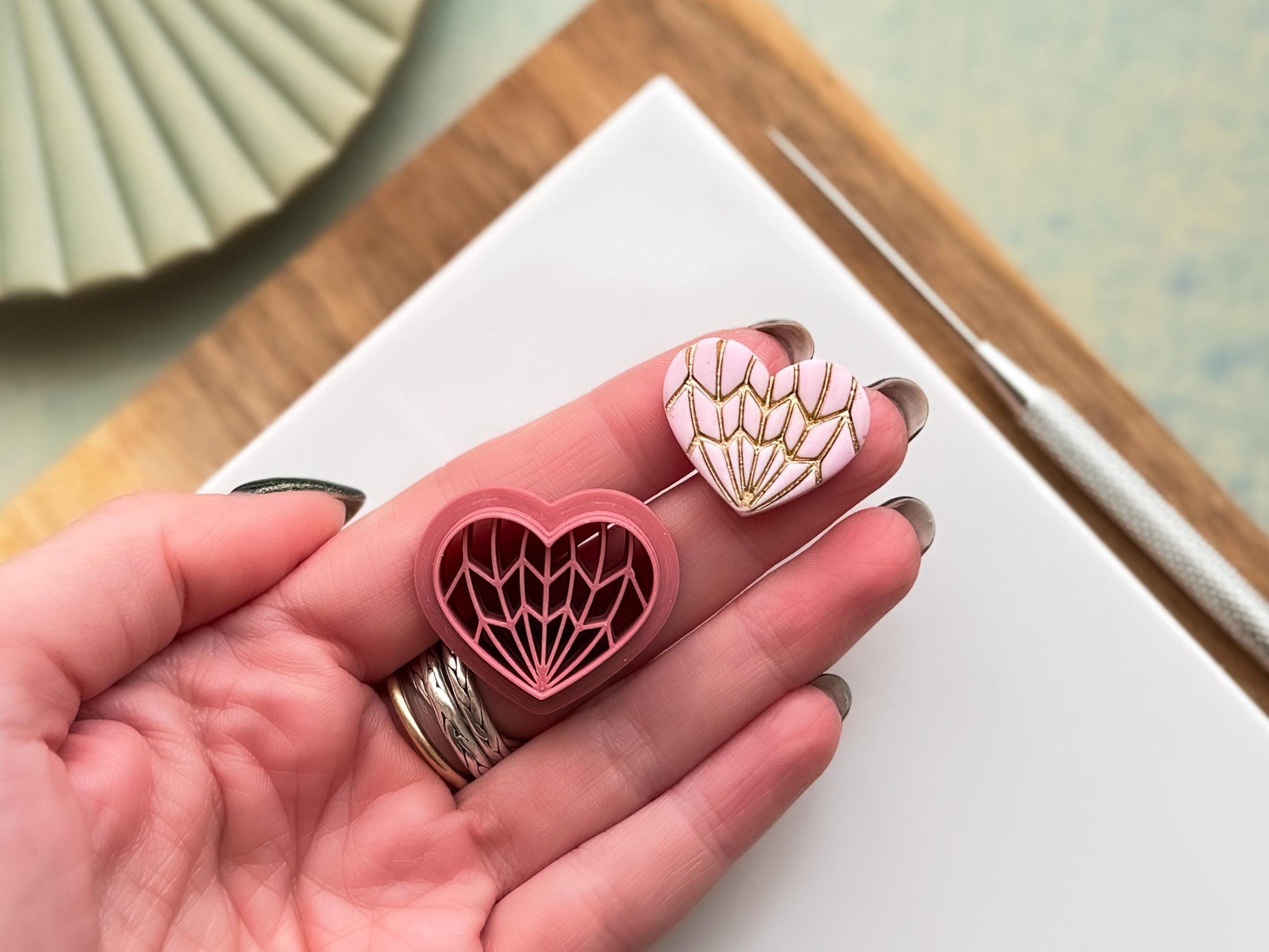 Geometric heart clay cutter set with intricate line design, alongside finished polymer clay heart with gold detailing