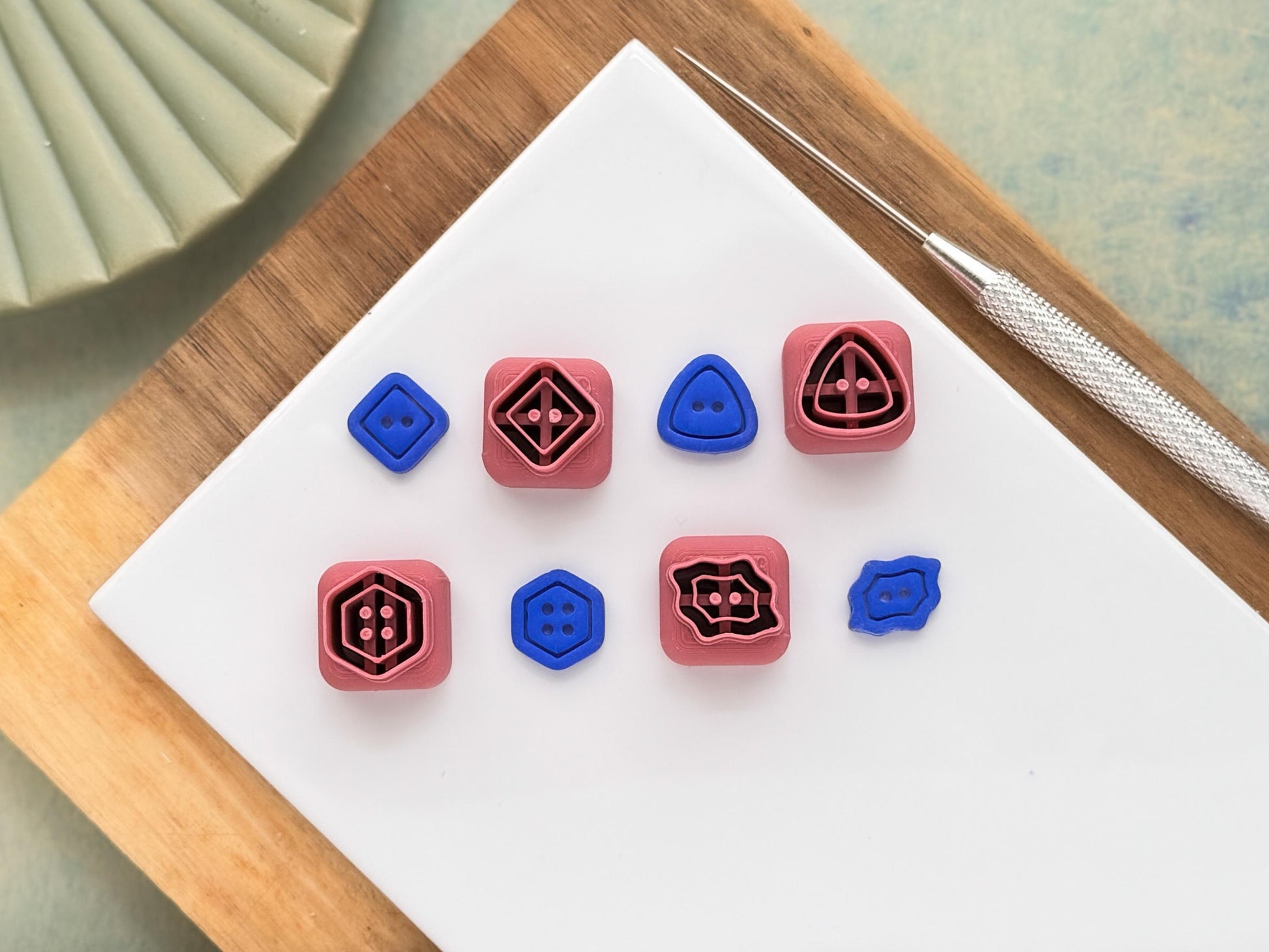 This image shows four button shaped polymer clay cutters, a hexagon, scalloped rectangle, a diamond shape and a triangle shape. Next to each of them is the corresponding clay cut out.