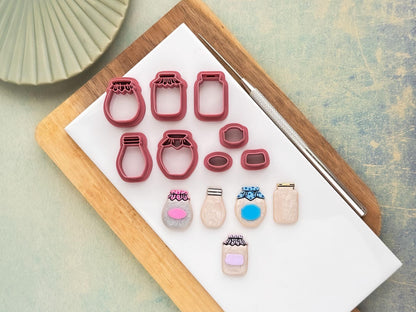 Set of 5 jar shaped clay cutters and 3 small label shaped cutters. Each jar is a different shape, three have cloth details and two have metal type screw lids. Next to the cutters is a set of polymer clay cut out samples made with the cutters.