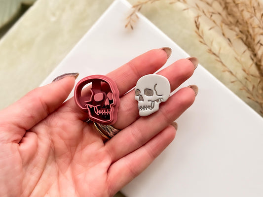 skull cutter and polymer clay cut out being held in a hand