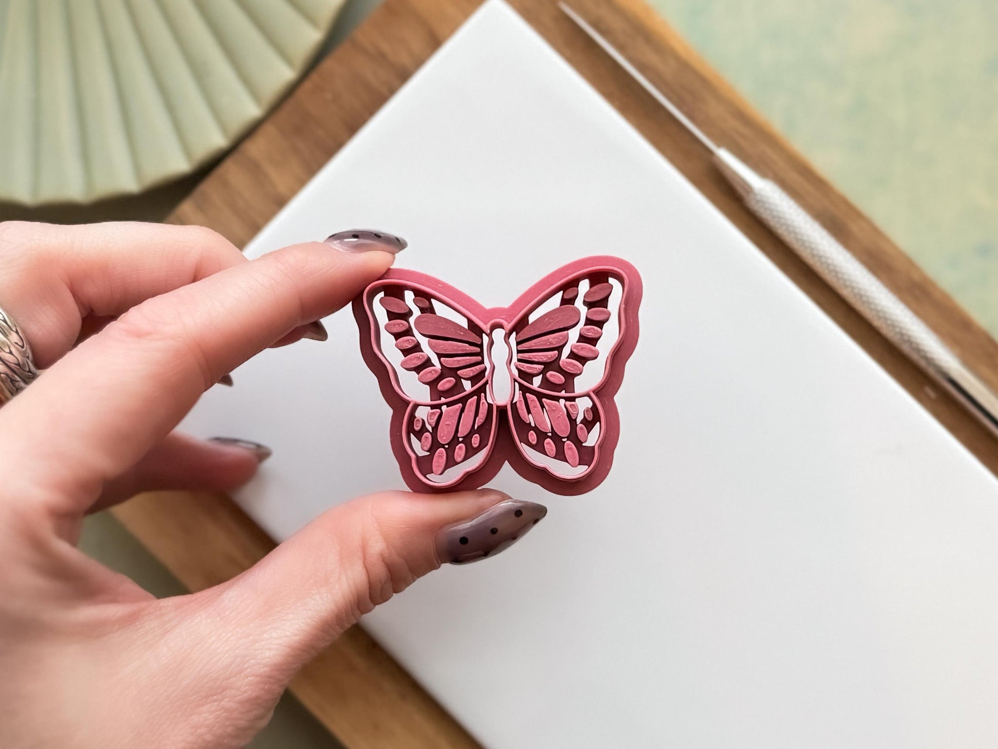 Intricate butterfly cutter for clay and fondant being held to show air flow