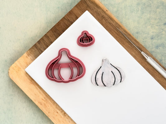 Garlic bulb shaped polymer clay cutters in small and large sizes with a sample cut out next to them showing the clove details.