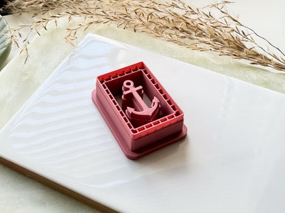 Side view of ocean themed clay cutter with anchor shaped stamp within a frame.