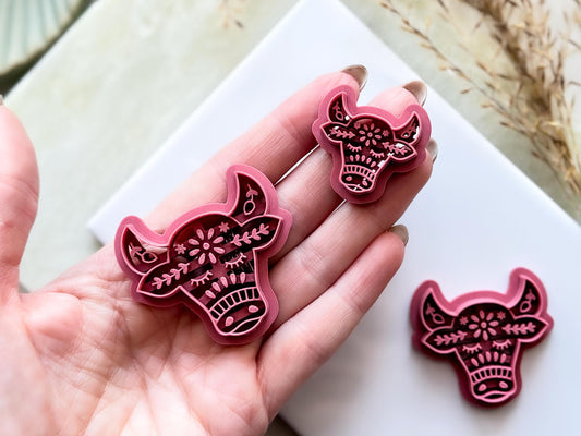 Bull shaped clay cutters with ears and horn details, featuring floral folk art style imprint stamps for making polymer clay earrings and jewellery