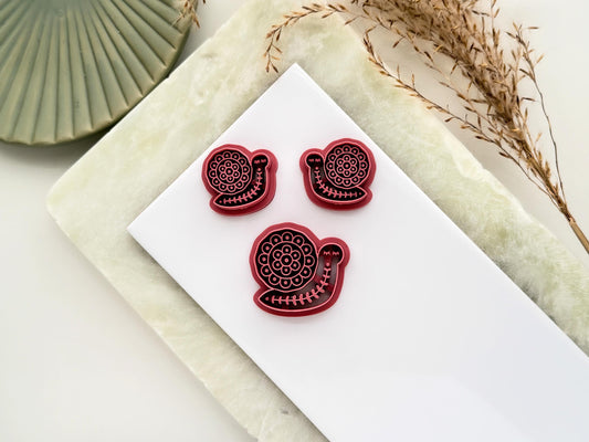 Boho snail cutter for polymer clay and fondant. The snail has a round shell and floral nordic style fol art imprint patterns. There is a large single cutter and a smaller mirrored pair of cutters for maing clay earrings.