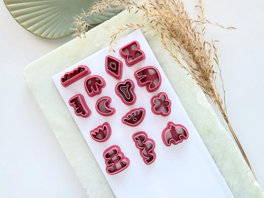Set of 14 abstract boho shaped clay cutters for making polymer clay earrings. The cutters are pink and feature wavy lines, curvy and organic shapes.