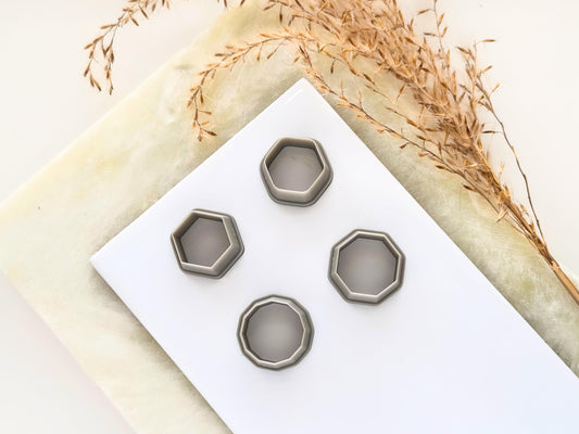 Four hexagon shaped clay cutters on a white tile