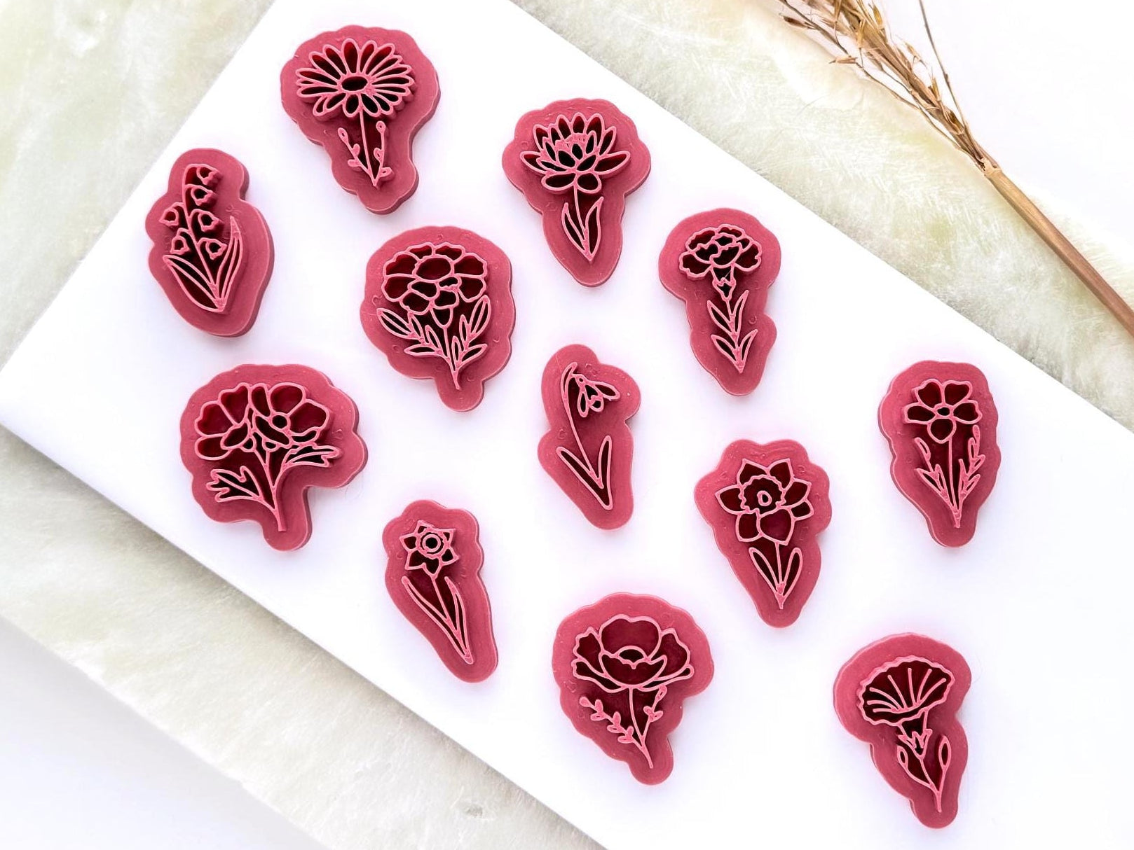 flower shaped stamps for polymer clay jewellery making. They are 3D printed in a pink material. There are 12 different flower shapes.