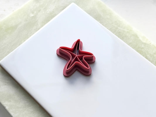 starfish shaped clay cutter in pink on white tile