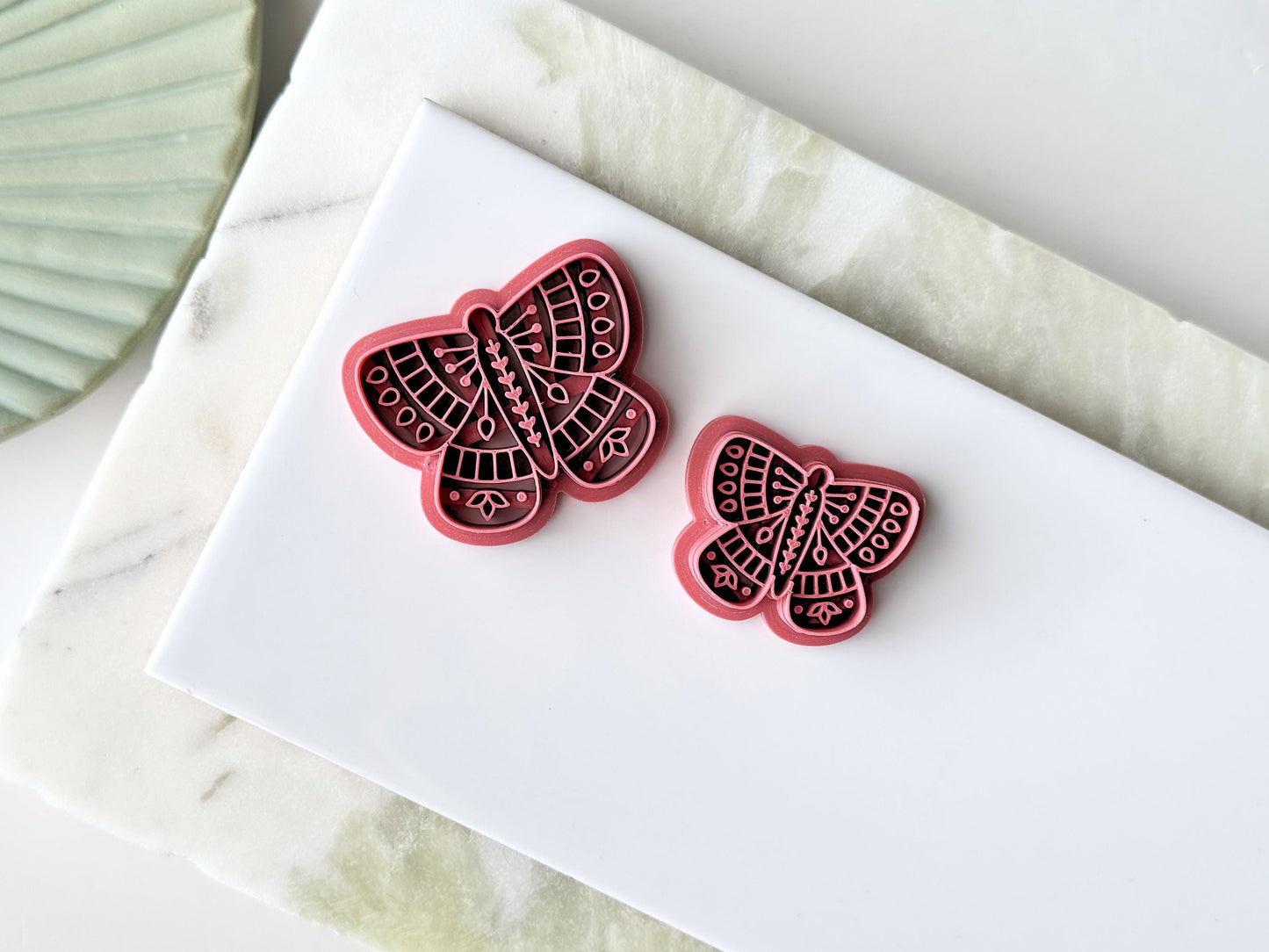 Two sizes of detailed butterfly polymer clay cutters showing 4 wings and bady with intricate floral and geometric stamp patterns